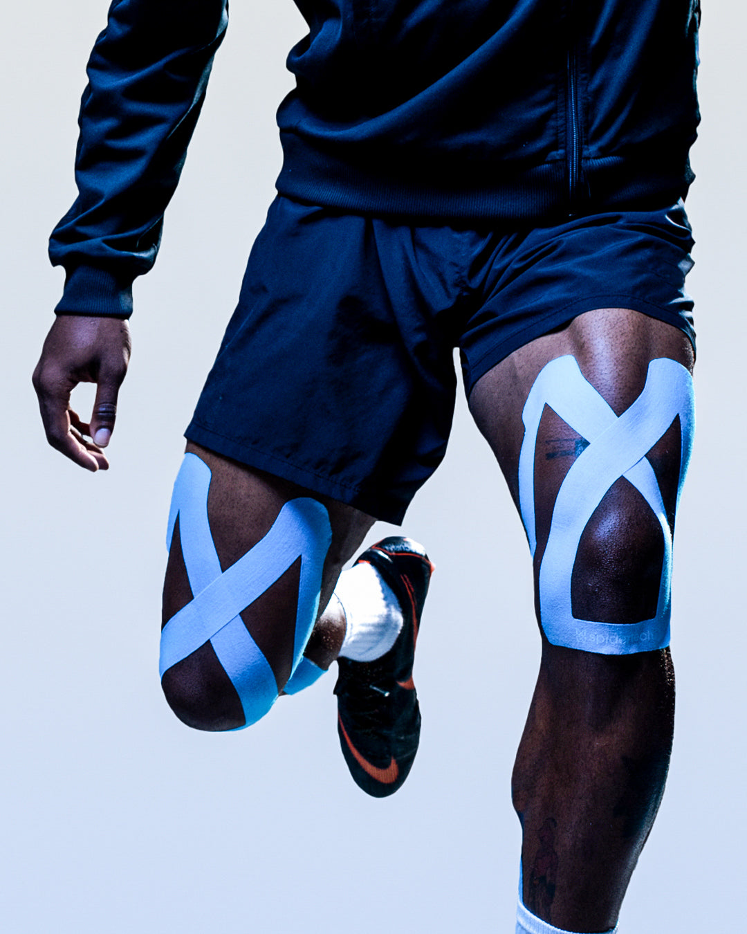 Soccer player sporting Spidertech Pro Knee tape on both knees